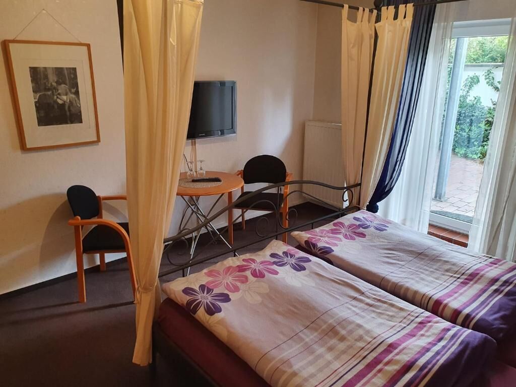 A hotel room with two beds, a desk with a chair, a television, and a framed picture on the wall.