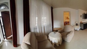 A compact living space with a sofa, a small round table, a kitchenette, and a dining area. - Hotel Jungmann (Saarlouis)
