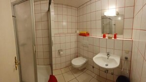 A small bathroom with a toilet, sink, and a mirror. - Hotel Jungmann (Saarlouis)