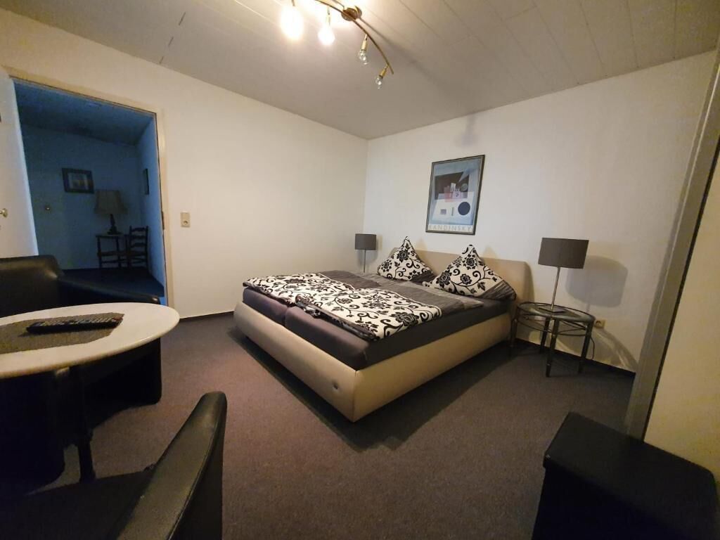 Une chambre à coucher avec un lit, un bureau, une chaise et une petite table.