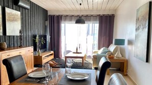 Een moderne woonkamer met een eethoek, houten meubels en kunst aan de muren.