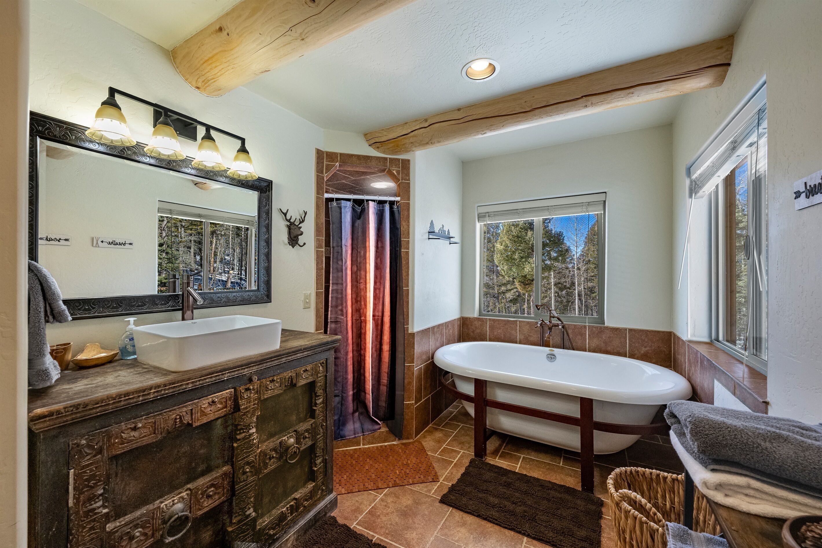 Une salle de bain avec un grand miroir, un lavabo, une baignoire et une fenêtre.