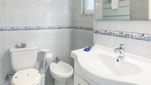 Ein Badezimmer mit Toilette, Bidet und einem großen Waschbecken mit Spiegel.