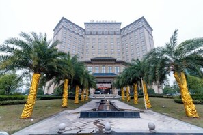 A hotel with a central courtyard, palm trees, and a fountain. - Fuxin International Hotel (Shangrao)