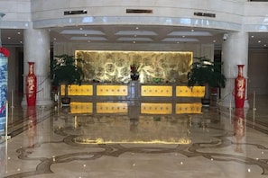A lobby with a reception desk, large columns, and a polished floor. - Fuxin International Hotel (Shangrao)