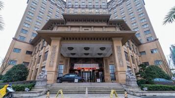 A multi-story building with a prominent entrance featuring a large archway and statues.