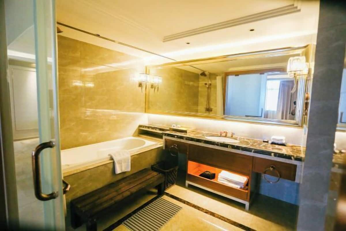A modern bathroom with a bathtub, a large mirror, and a vanity with a sink and countertop.