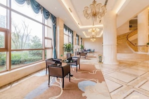 A spacious hotel lobby with a grand staircase, large windows, and a chandelier. - Fuxin International Hotel (Shangrao)
