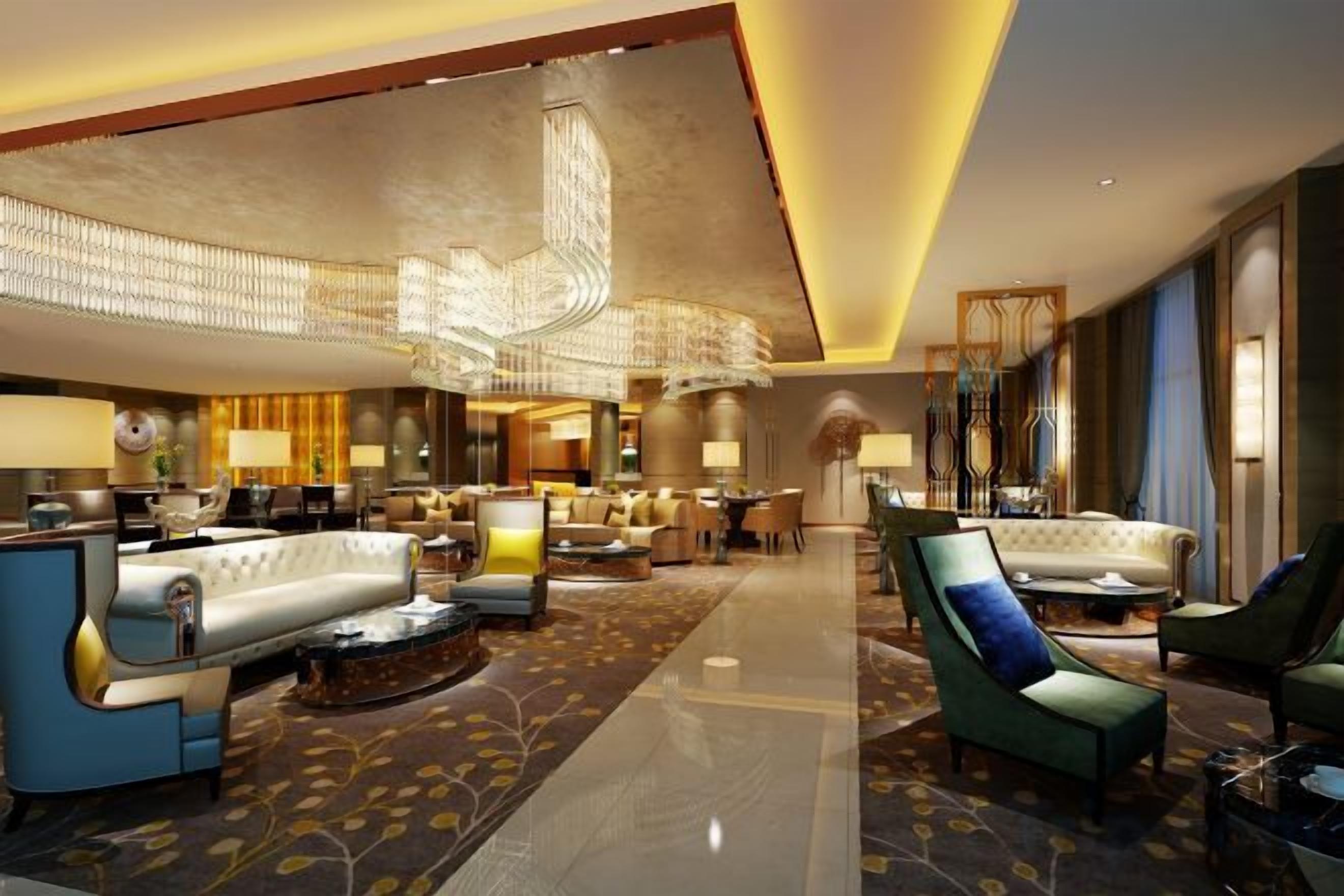 A spacious lobby with a modern chandelier, seating areas, and a well-lit ambiance.