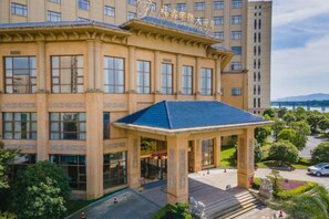 A multi-story building with a central entrance, large windows, and a covered outdoor area. - Fuxin International Hotel (Shangrao)