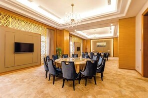 A conference room with a round table, chairs, a flat-screen TV, and a chandelier. - Fuxin International Hotel (Shangrao)