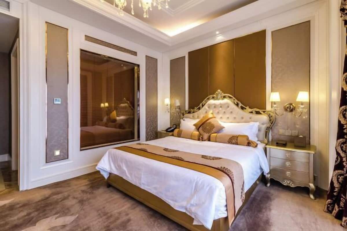 A spacious bedroom with a large bed, a nightstand, a mirror, and a wardrobe.