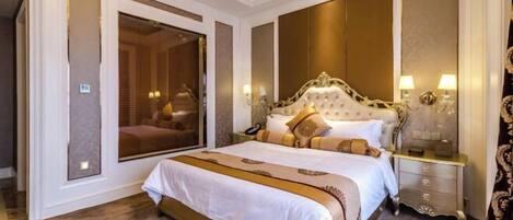 A spacious bedroom with a large bed, a nightstand, a mirror, and a wardrobe.