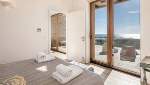 A bedroom with a large sliding glass door leading to a balcony with a view of the sea. - Casa le Cicale the top villa in Falasarna,Basketbal,pool,BBQ (Phalasarna)