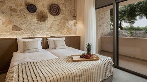 Un dormitorio con pared de piedra, dos camas, una bandeja de fruta y vistas al exterior.