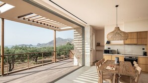 Una cocina moderna con una isla grande, un comedor con mesa de madera y un balcón con vistas a las montañas.