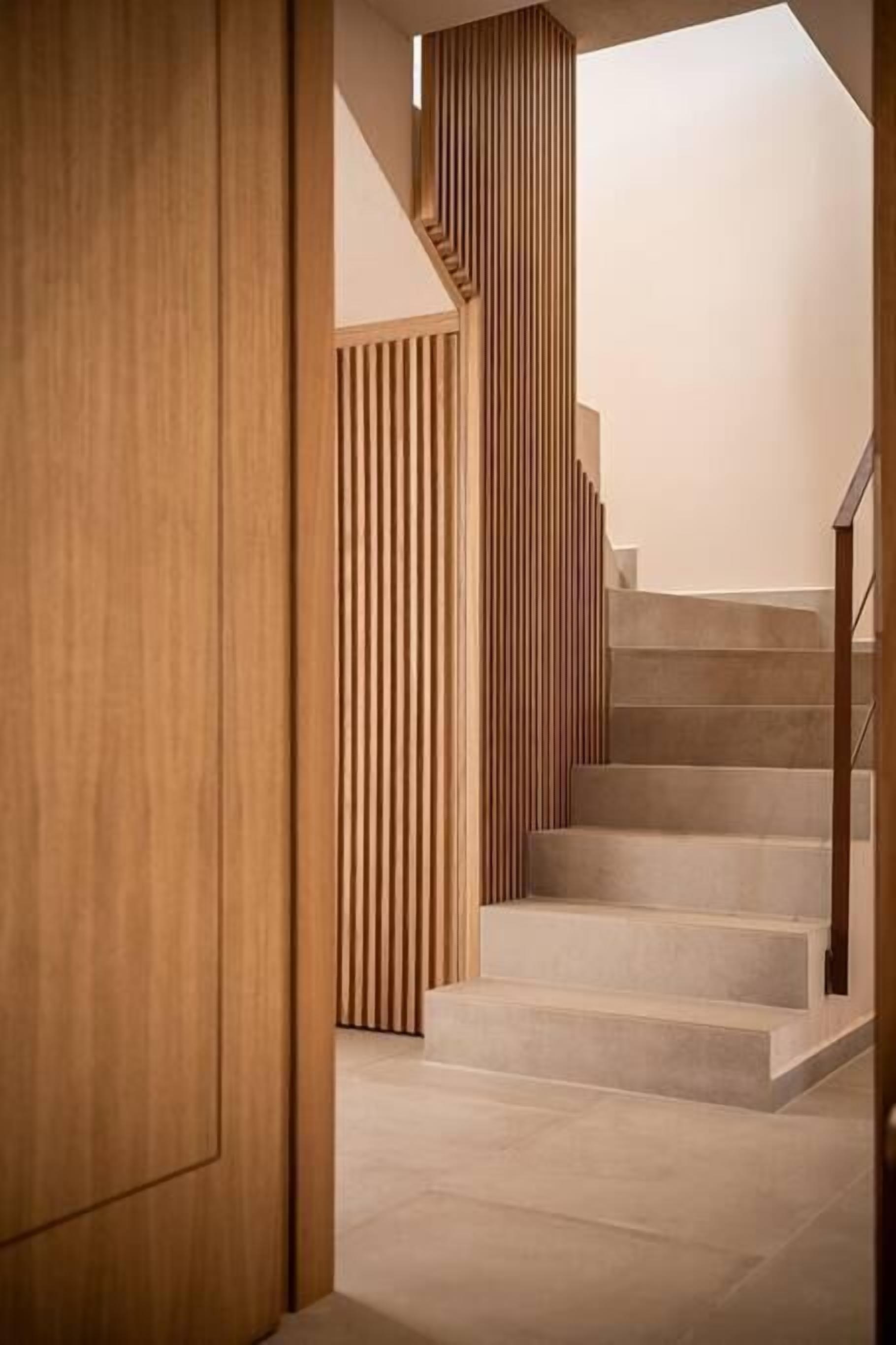 Eine moderne Treppe mit Holzpaneelen auf einer Seite und einer schlichten Wand auf der anderen.