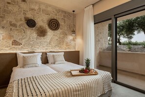 A bedroom with a stone wall, two beds, a tray with fruits, and a view of the outdoors.
