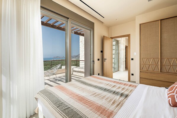 Une chambre avec un lit, une vue sur la mer et une porte-fenêtre coulissante donnant sur un espace extérieur.