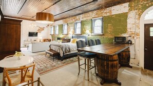 Een knus, rustiek slaapkamer met een groot bed, een eethoek met een houten tafel en een kitchenette.