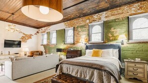 Een slaapkamer met een bed, een bankje, een kapstok en een televisie.