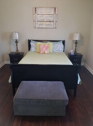 Une chambre à coucher comprenant un lit, deux tables de chevet, un banc et un élément décoratif mural.