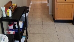 A narrow hallway with a kitchen area on the right, featuring wooden cabinets and a countertop. A sign on the wall reads "HEY Y'ALL".