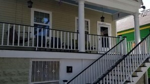 A two-story building with a covered porch, a staircase, and a gated entrance.