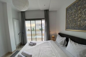 Ein modernes Hotelzimmer mit einem großen Bett, Blick aus dem Fenster und einem Bild an der Wand.