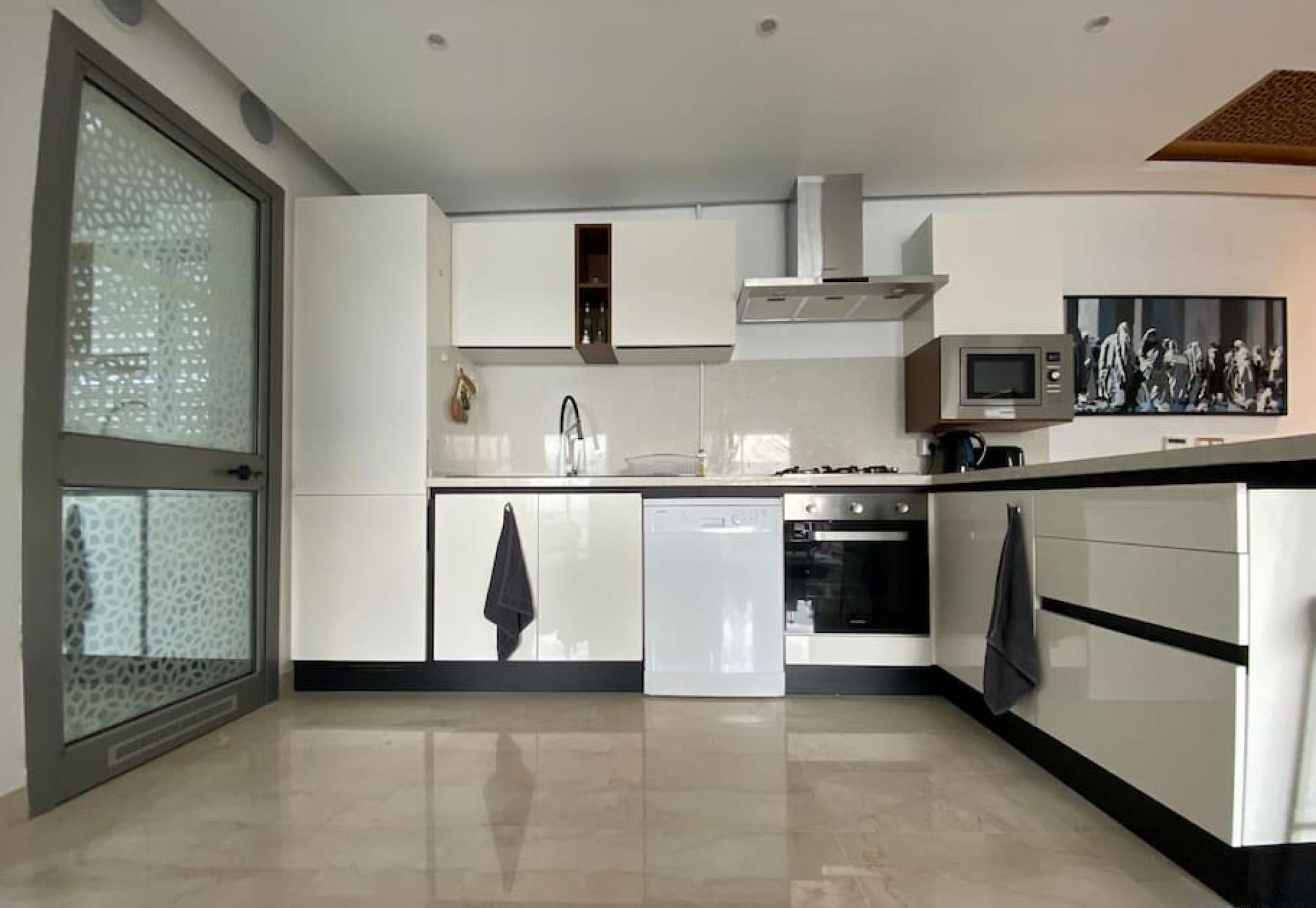 A modern kitchen with white cabinetry, a dishwasher, an oven, and a microwave.