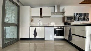 A modern kitchen with white cabinetry, a dishwasher, an oven, and a microwave. - El Badira Apt de Luxe Sidi Daoud la Marsa (La Marsa)