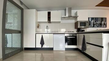 A modern kitchen with white cabinetry, a dishwasher, an oven, and a microwave.