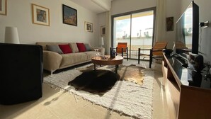 A modern living room with a sofa, coffee table, and a flat-screen TV. - El Badira Apt de Luxe Sidi Daoud la Marsa (La Marsa)