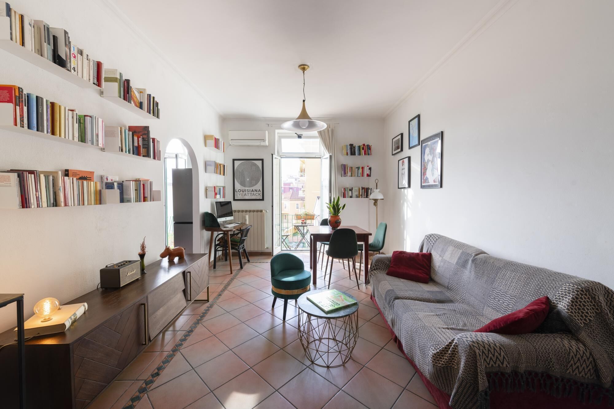 A living room with a sofa, a dining table, and a bookshelf filled with books.