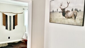 Huoneessa on kehystetty valokuva villieläimestä, seinälle ripustettu tekstiilitaideteos ja lehmännahkamatto.