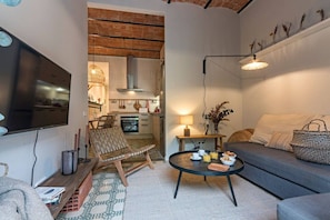 A cozy living room with a sofa, a coffee table with breakfast items, a TV, and a chair.