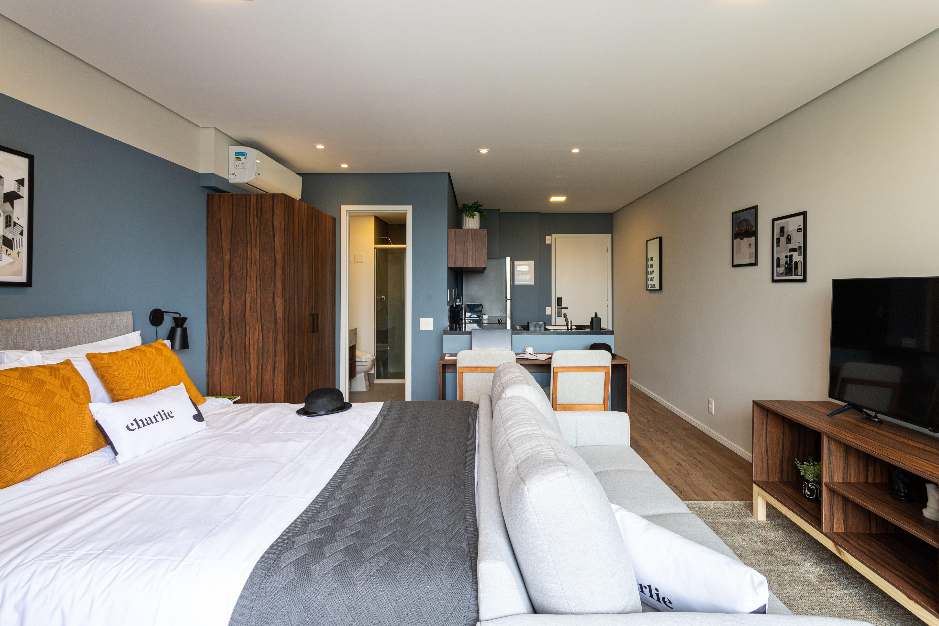 Una habitación de hotel moderna con una cama grande, un sofá, un escritorio y un televisor.