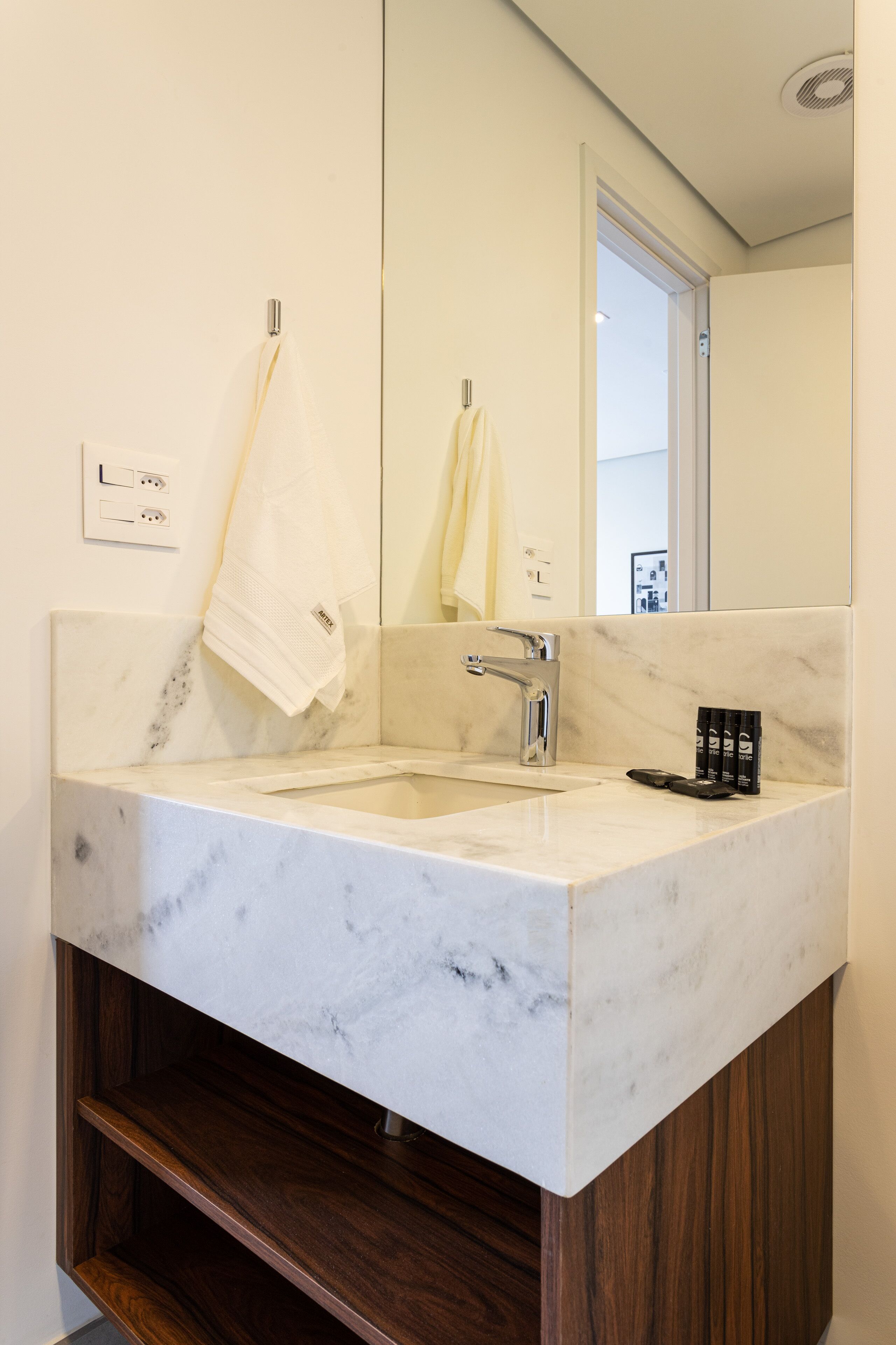 A bathroom with a marble sink, wooden vanity, and a mirror.