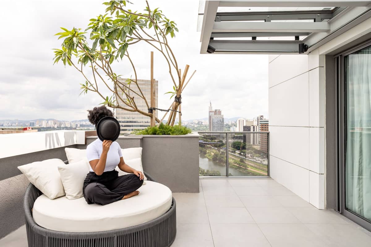 A modern balcony with a round seating area, a potted plant, and a city view.
