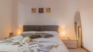 A neatly made bed with pillows, a bedside table with a lamp, a bedside scale, and a wall with three artworks. - casa_andrea_varenna_varennaholidays (Perledo)