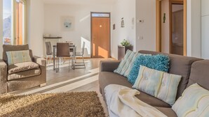 A living room with a sofa, armchairs, and a dining area with a table and chairs. - casa_andrea_varenna_varennaholidays (Perledo)