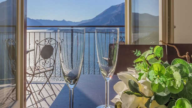 Two glasses of champagne on a balcony with a view of mountains and a body of water. - casa_andrea_varenna_varennaholidays (Perledo)