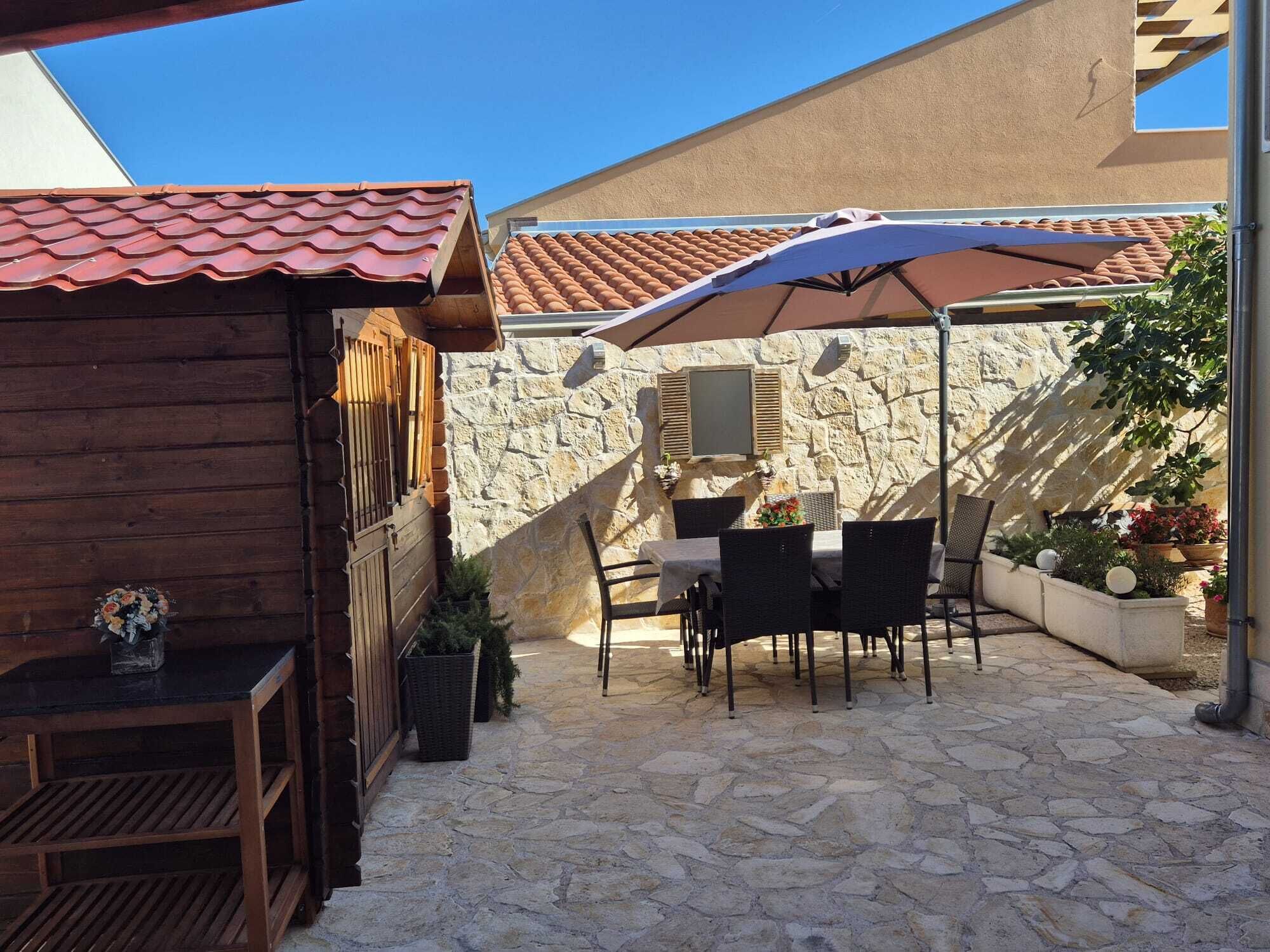 A patio with stone flooring, a table with chairs, and an umbrella.