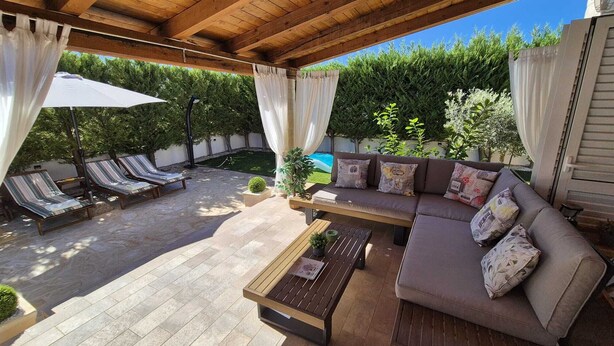 Eine Terrasse im Freien mit Holzboden, gepolsterten Sitzgelegenheiten und Fliesenböden.