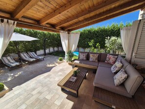 Eine Terrasse im Freien mit Holzboden, gepolsterten Sitzgelegenheiten und Fliesenböden.