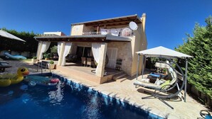 Ein zweistöckiges Haus mit Pool, Gartenmöbeln und einer überdachten Terrasse.