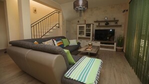 Ein Wohnzimmer mit Sofa, Fernseher und einer Treppe.