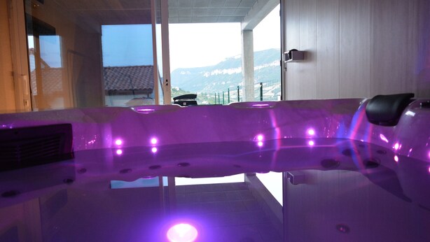 A hot tub with purple lighting, a view of mountains, and a tiled floor.