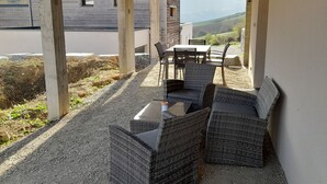 An outdoor patio area with wicker furniture, a table, and a view of the countryside.