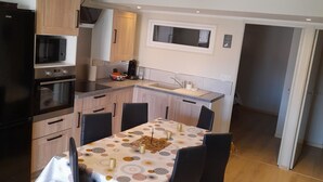 A modern kitchen with a dining area, featuring a microwave, oven, and a built-in window above the sink.